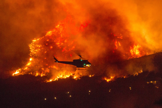 A helicopter prepares to drop water at a wildfire in Yucaipa, Calif., on Saturday as three fast-spreading wildfires sent people fleeing, one of them trapping campers at a reservoir in Sierra National Forest.