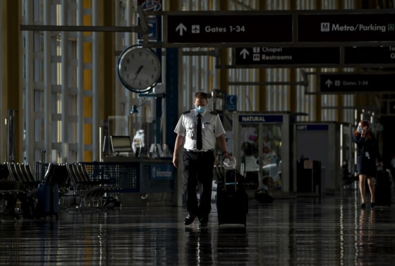 A pilot wearing a protective mask walks through Ronald Reagan National Airport in Arlington