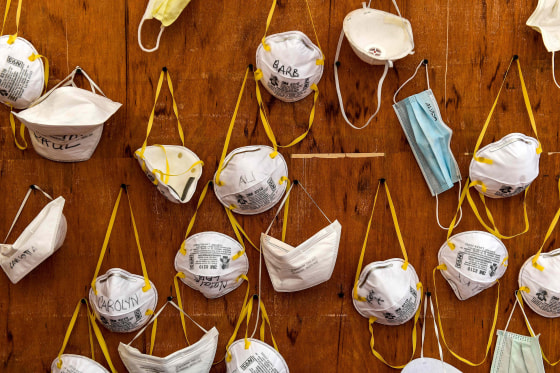 Image: Protective masks bearing the names of medical staffers and nurses are pictured pinned to a wall on April 2, 2020 at the operative field hospital for coronavirus patients, outside the Cremona hospital, Lombardy