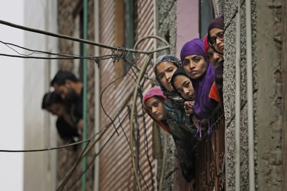 Image: Indian Muslim women look out of a window as security officers patrol a street in New Delhi, India