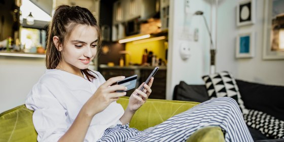 Young woman with mobile phone and credit card at home