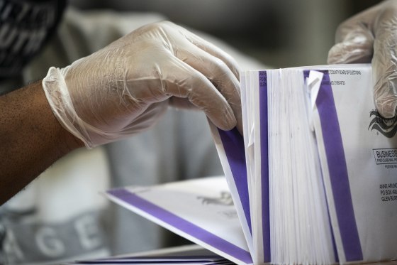 Image: A canvasser wears gloves while processing mail-in ballots in a warehouse at the Anne Arundel County Board of Elections headquarters