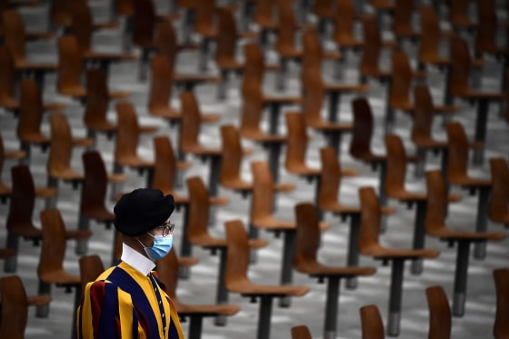 Image: A Swiss guard wearing a face mask stands in an almost empty Paul Vi Hall during Pope Francis limited public audience at the Vatican