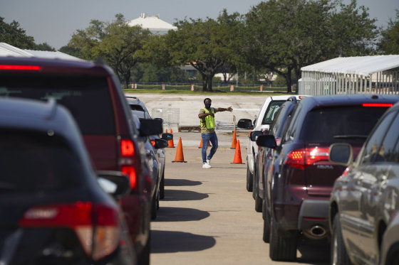 Image: An election worker guides voters in cars at a drive-through mail ballot drop-off site at NRG Stadium on Oct. 7, 2020 in Houston, Texas.