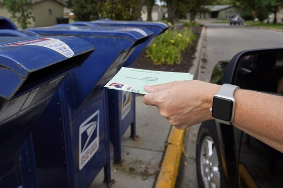 Image: A person drops applications for mail-in ballots into a mailbox in Omaha, Neb., on Aug. 18, 2020.