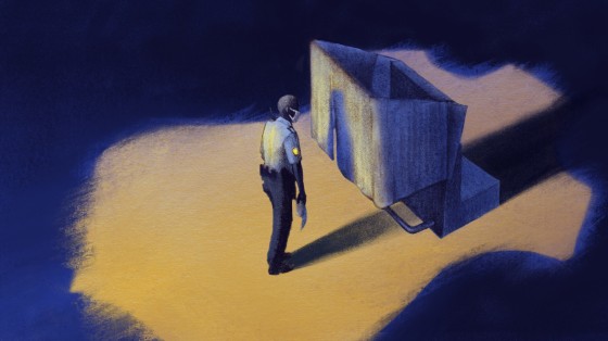 Image: A police officer waits to cast a ballot while the spotlight in the shape of a police badge illuminates him.