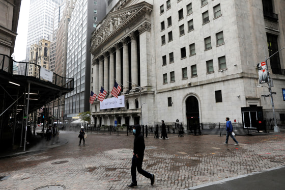 Image: People wearing protective face masks walk outside New York Stock Exchange in New York