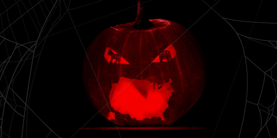 Image: A lit up carved pumpkin with a US shaped mouth and GOP and Democrat symbol shaped eyes.