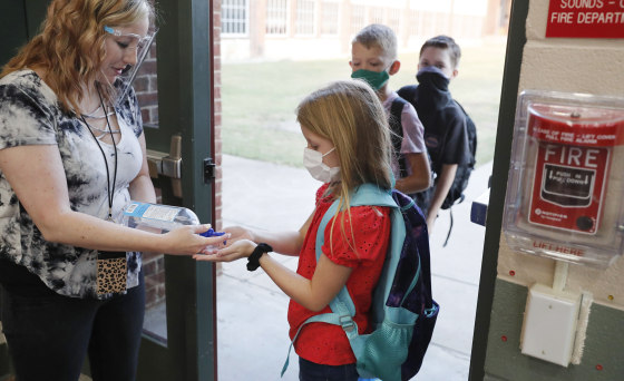 Wearing masks to prevent the spread of Covid-19, elementary school students use hand sanitizer before entering school for classes in Godley, Texas, on Aug. 5, 2020.
