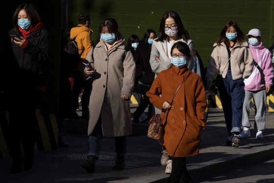 Image: People walk in a street during morning rush hour following an outbreak of the coronavirus disease (COVID-19) in Beijing