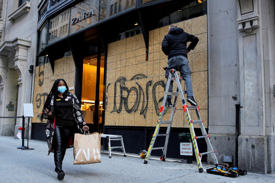 Image: Shopper passes as workers board up a store ahead of election results in Manhattan, New York