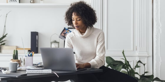 Mid adult woman working in her home office, using laptop