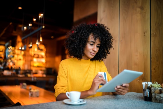 Image: A woman uses her credit card for online shopping.