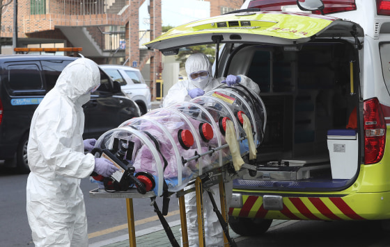 Image: Medial workers carry a patient infected with the coronavirus onto an ambulance at an elderly care facility in Ulsan, South Korea