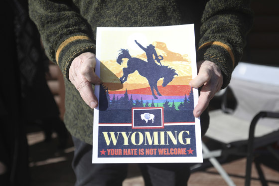 Image: Colin Monahan holds a poster that reads \"Wyoming, your hate is not welcome\" at her home in Wapiti, Wyo.