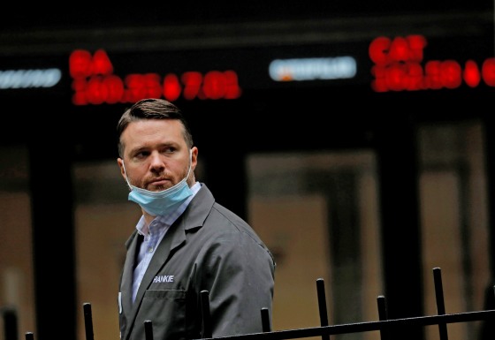 A trader walks past a digital stock price display outside the New York Stock Exchange on Oct. 26, 2020.