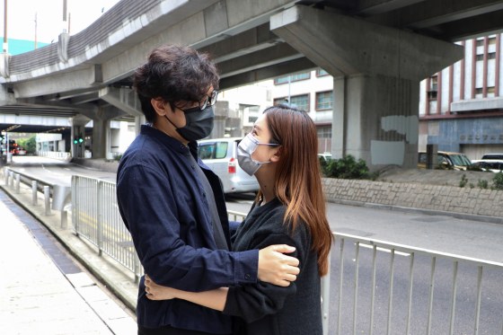 Image: Pro-democracy activist Sam Cheung hugs his wife before reporting to the police station over national security law charges, in Hong Kong