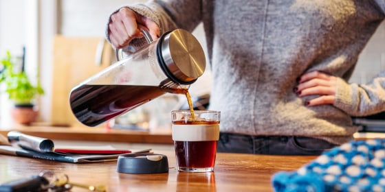 Woman pouring cold brew in her kitchen from her cold brew maker