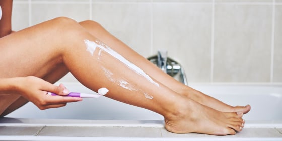Woman shaving her legs in the bathroom