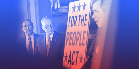 Image: Chuck Schumer stands next to a board that reads,\"For the People Act\".