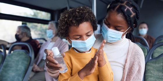 Mother giving her son hand sanitizer while on a bus