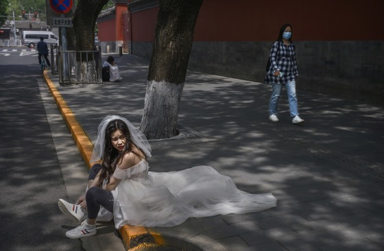 Image: A Chinese woman puts on her sneakers after taking pictures in advance of her wedding near the Forbidden City