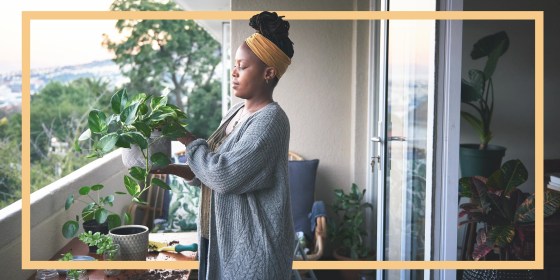 Woman gardening on her balcony wearing a grey cardigan and yellow headband