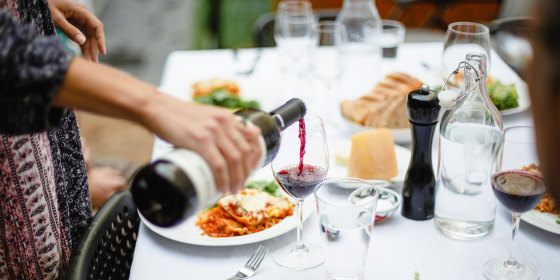 Woman pouring red wine at dinner