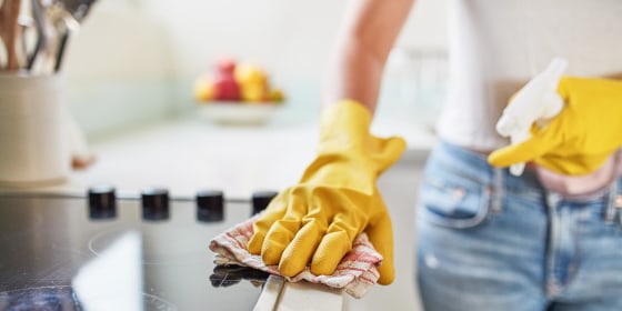 Woman wiping her counters down, wearing yellow cleaning gloves