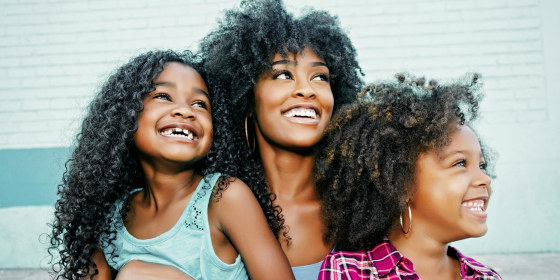 Mother and her two daughters sitting on her lap looking away