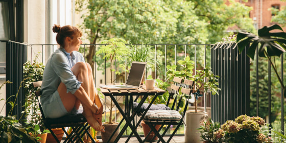 Smiling woman looking at her laptop on balcony