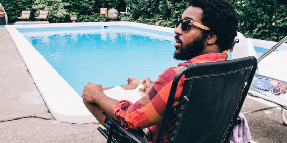 Man relaxing on a black chair by the pool