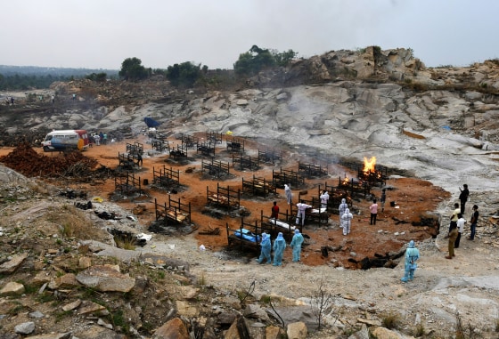 Image: Volunteers and relatives prepare to cremate the bodies of people who died due to Covid-19 at a crematorium ground in Giddenahalli village on the outskirts of Bengaluru