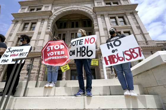 Image: People opposed to Texas voter bills HB6 and SB7 hold signs during a news conference hosted by Texas Rising Action on the steps of the State Capitol on April 21, 2021, in Austin, Texas.