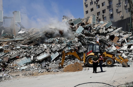 Workers clear rubble from a building that was destroyed by an Israeli airstrike on Saturday that housed The Associated Press, broadcaster Al-Jazeera and other media outlets, in Gaza City on May 16, 2021.