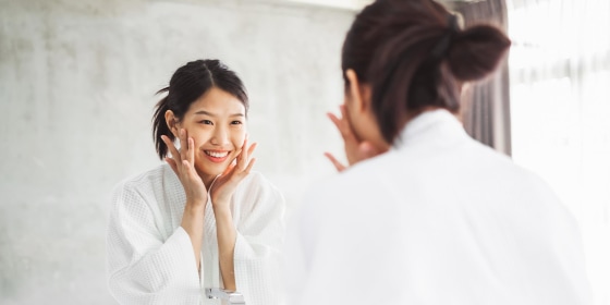 Woman Looking At Her Face On Mirror In Bathroom