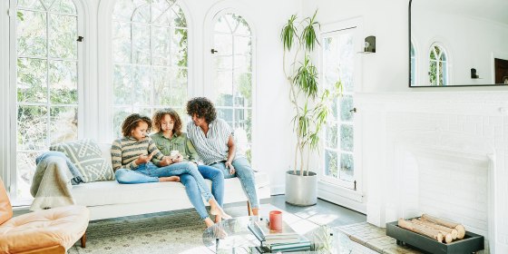 Mother and daughters sitting in living room watching video on smart phone