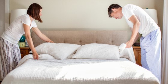 Couple arranging bed at home in their pajamas