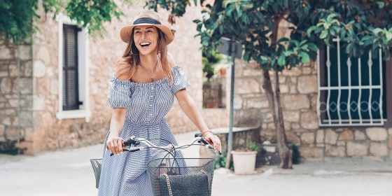 Woman with a bicycle, wearing a hat and blue dress