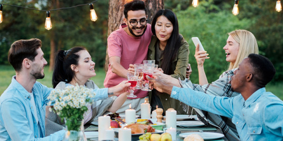 Group of intercultural cheerful friends gathered together by served table