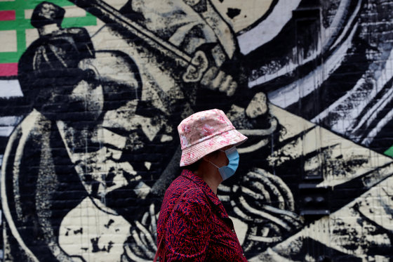 Image: A woman wearing a protective face mask walks by a mural following the May 31, 2021 unprovoked attack on a 55 year old Asian woman, in Manhattan's Chinatown district of New York City