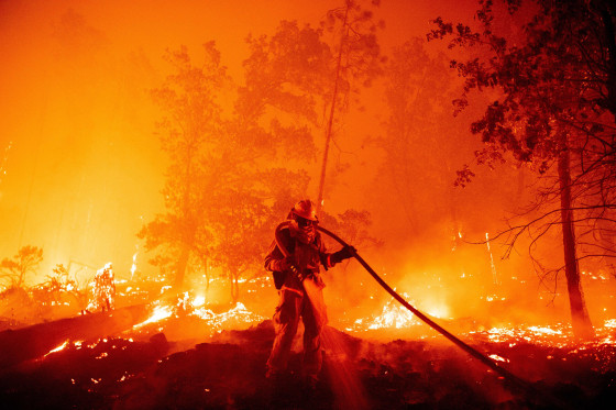 Image: A firefighter douses flames as they push towards homes in California