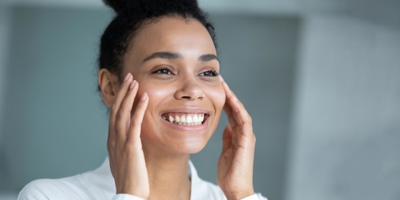 Woman touching her face while looking in the mirror