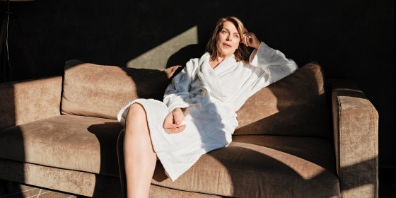 Thoughtful senior woman looking away while relaxing on sofa in hotel