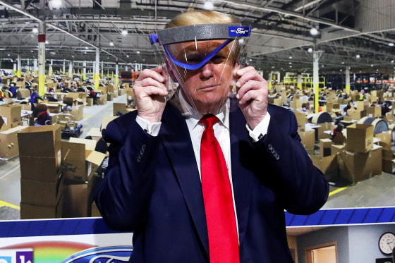 President Donald Trump holds up a protective face shield that was handed to him during a tour at the Ford Rawsonville Components Plant in Ypsilanti, Mich., on May 21, 2020.