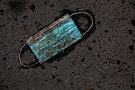 IMage: A discarded surgical mask on an asphalt street.