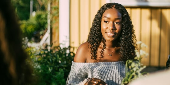 Smiling female looking at friend while sitting in yard