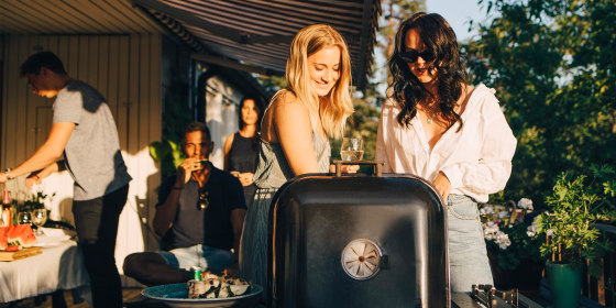 Female friends talking while grilling food on barbecue in dinner party
