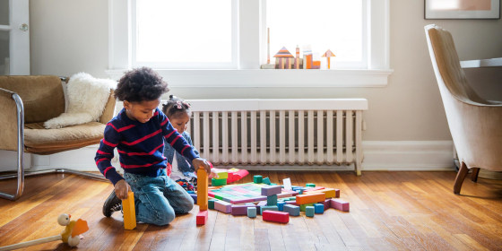 Brother and sister playing on floor at home with blocks