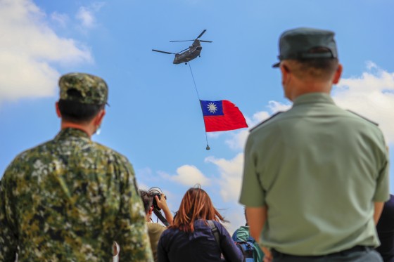 Taiwanese soldiers stand guard as a Chinook Helicopter carrying a tremendous Taiwan flag flies over a military camp as part of a rehearsal for Taiwan's Double-Ten National Day Celebration on Sept. 28, 2021.